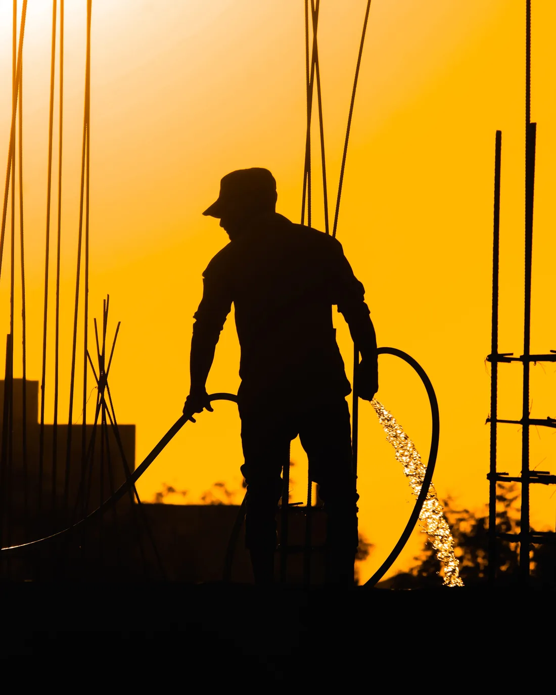A construction worker building at golden hour, amid rebar and scaffolding